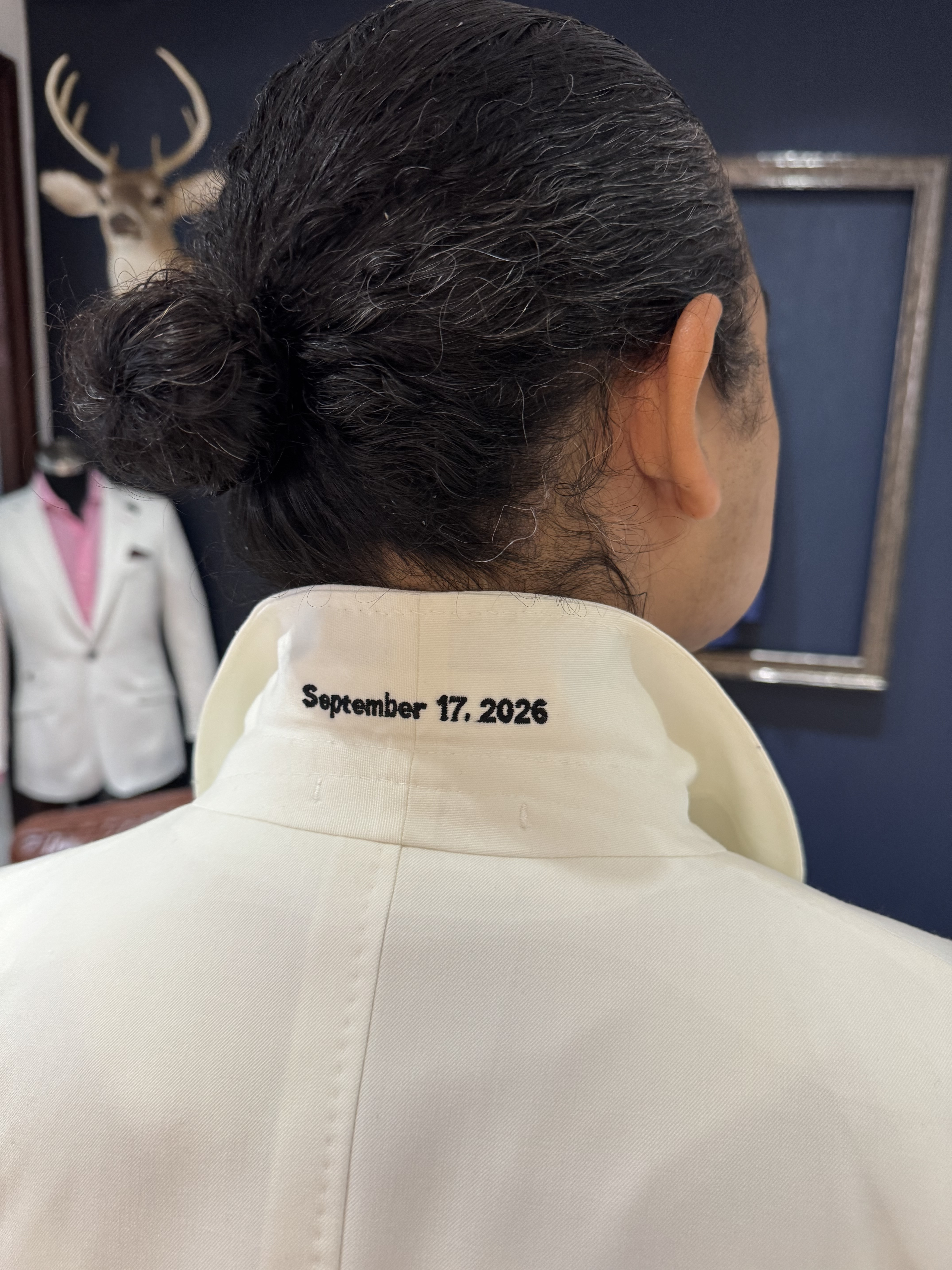 Custom embroidery inside the collar of a cream dinner jacket showing the wedding date September 17, 2026