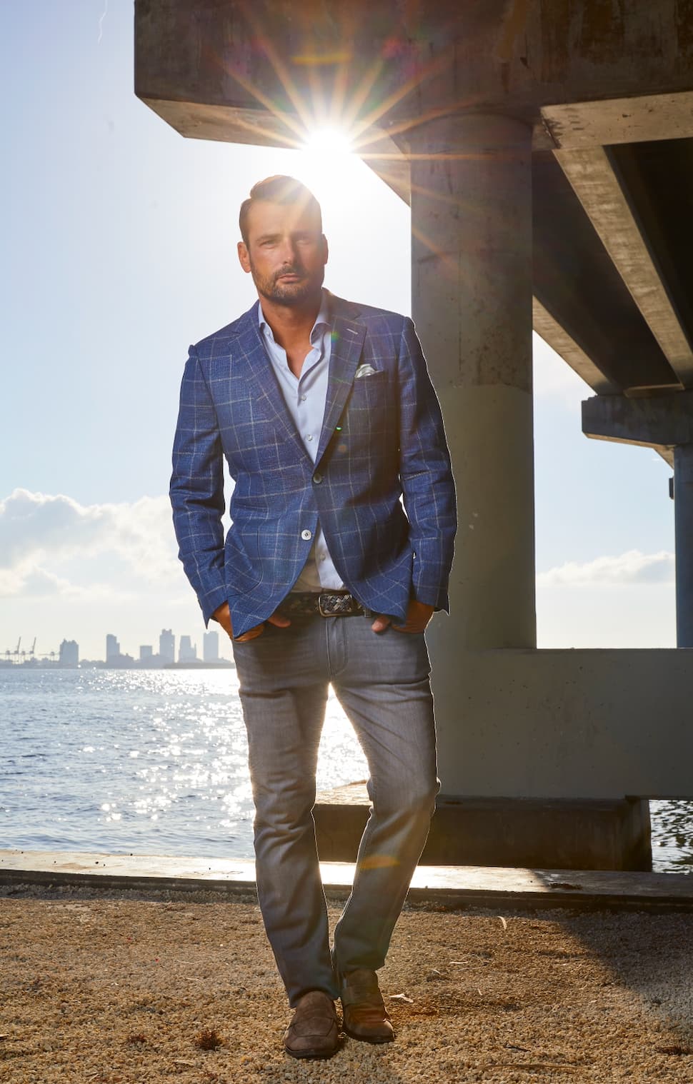 Man wearing a blue windowpane sport jacket with grey trousers and brown loafers styled for a smart casual look