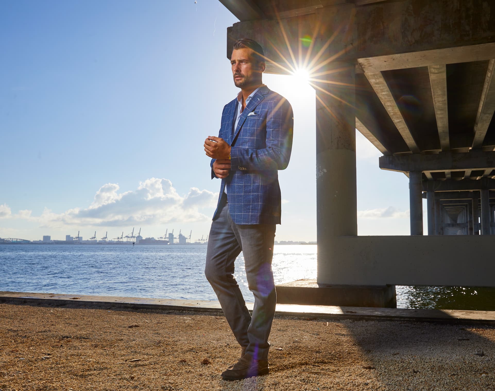 Blue windowpane sport jacket with grey trousers styled at sunset near the waterfront