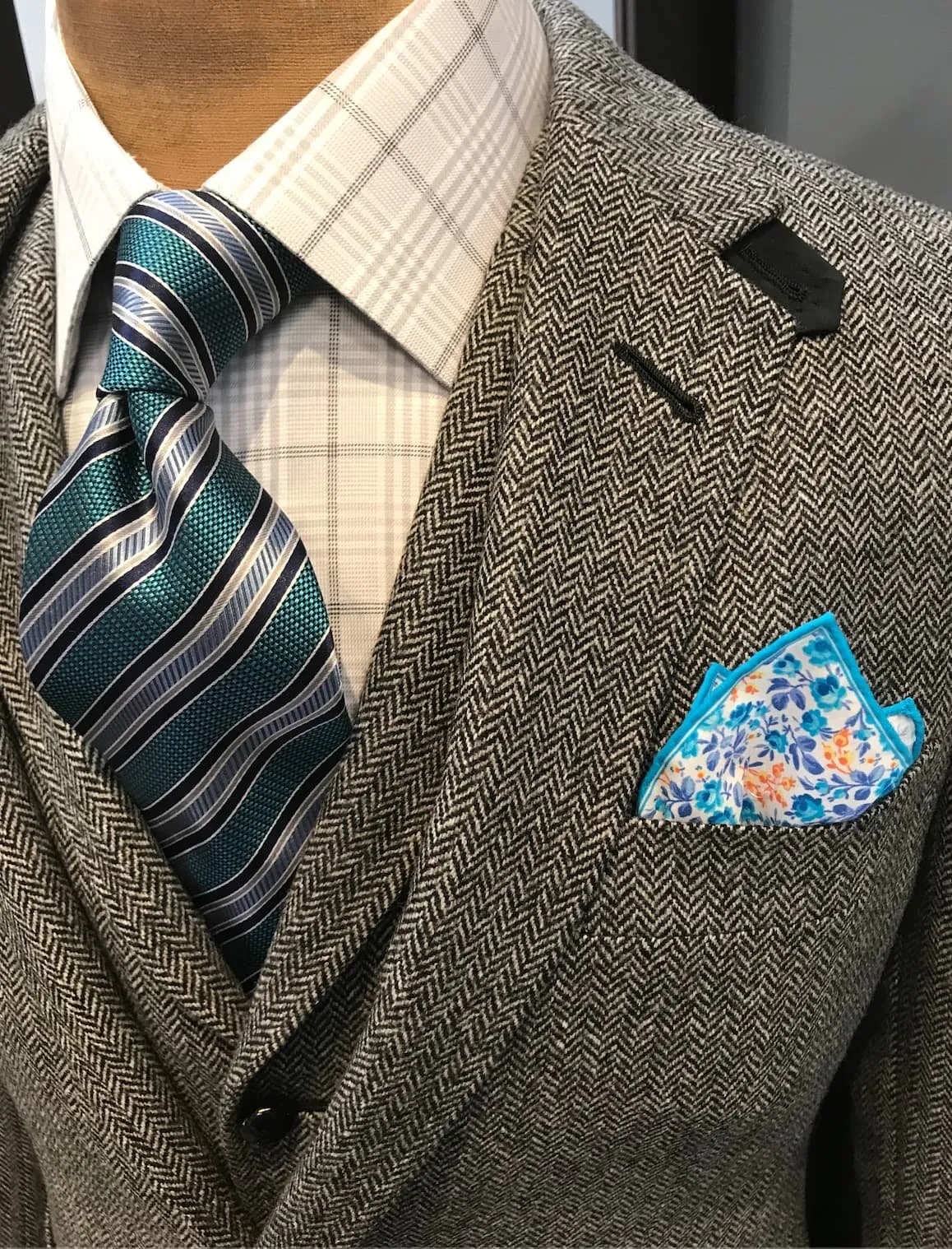 Grey herringbone wool sport jacket with patterned tie and floral pocket square, a classic cold-weather tailoring combination