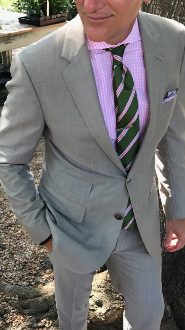 A man wearing a light grey summer suit that is ideal for Miami's year round warm climate and business dress codes.