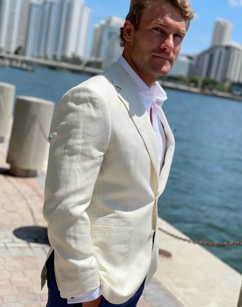 Man wearing a cream linen blazer by the waterfront in Miami for summer styling