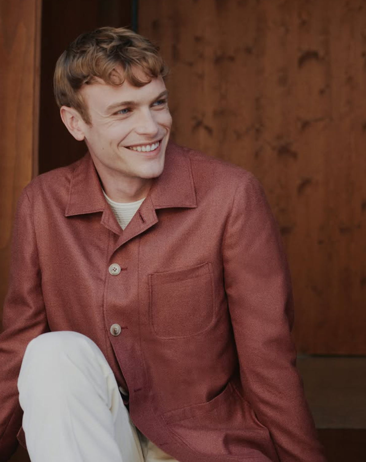 Close-up detail of a rust wool shirt jacket showing texture, buttons, and patch pocket construction
