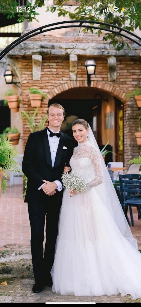 Bride and groom in formal wedding attire posing at brick archway venue