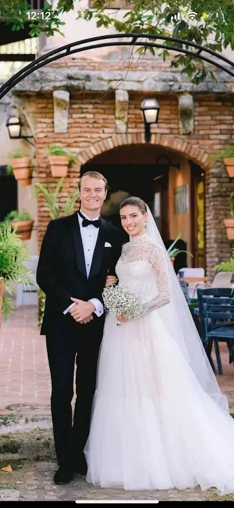 Bride and groom in formal wedding attire posing at brick archway venue