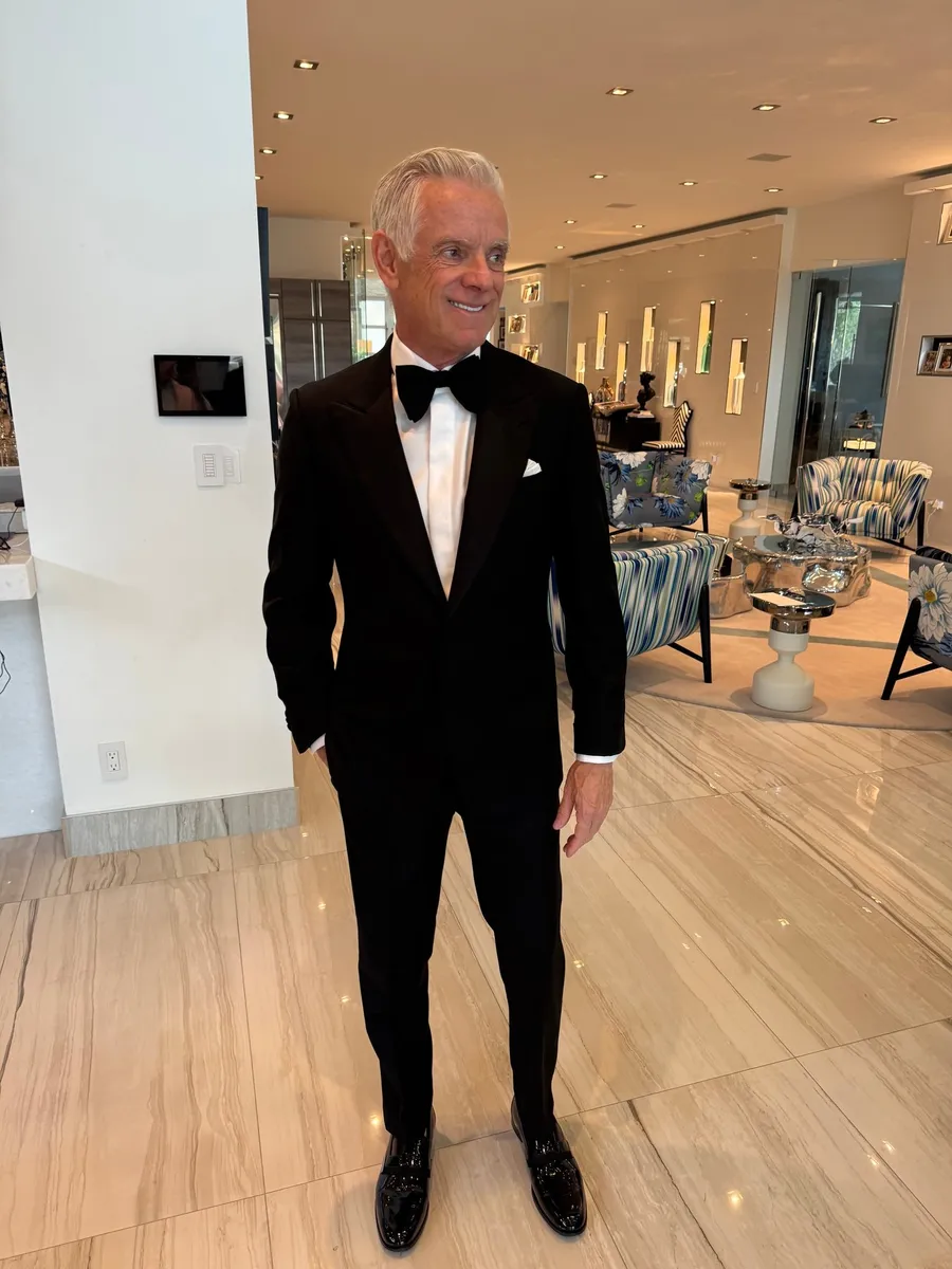Client in black tuxedo standing in modern luxury lobby at formal event