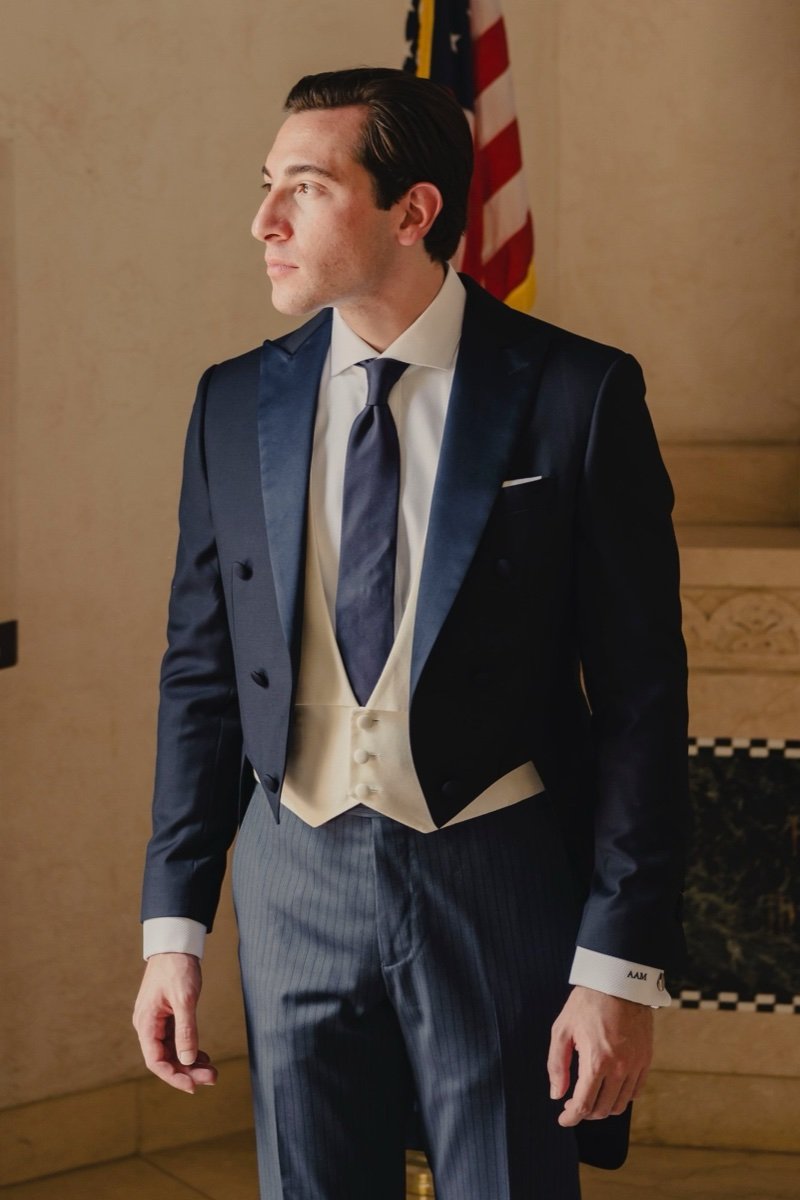 Man wearing a navy blue tailcoat with peak lapels and ivory waistcoat for formal evening attire