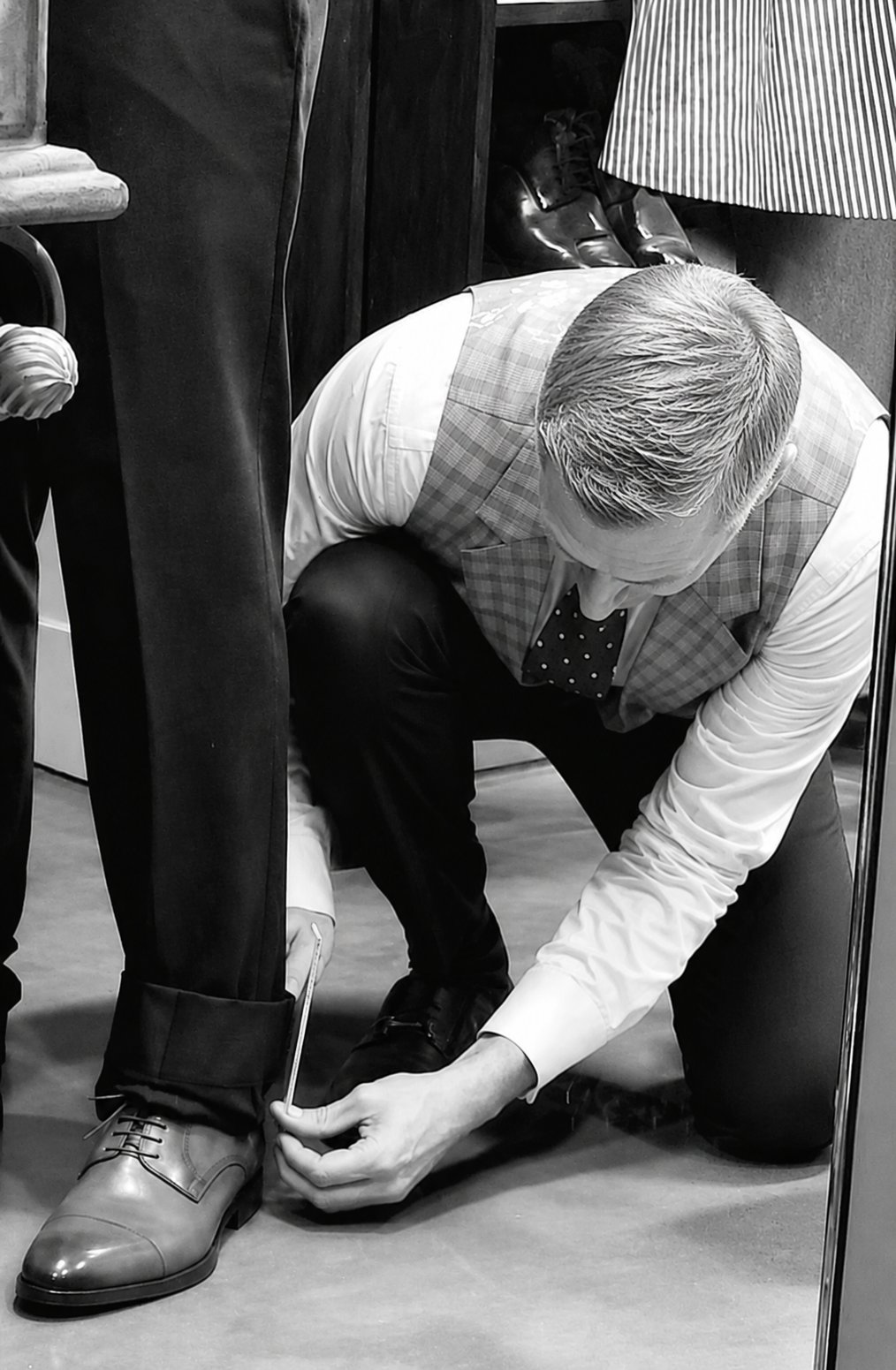 Master clothier taking precise measurements for a custom suit fitting