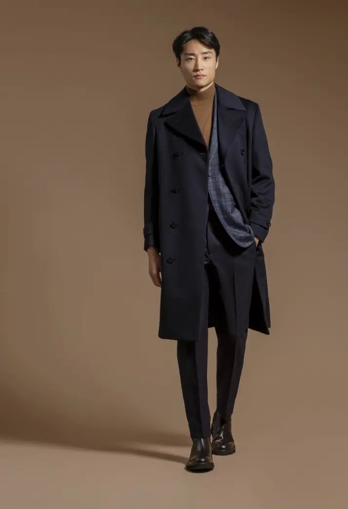 Navy double-breasted polo coat layered over a camel turtleneck and windowpane blazer