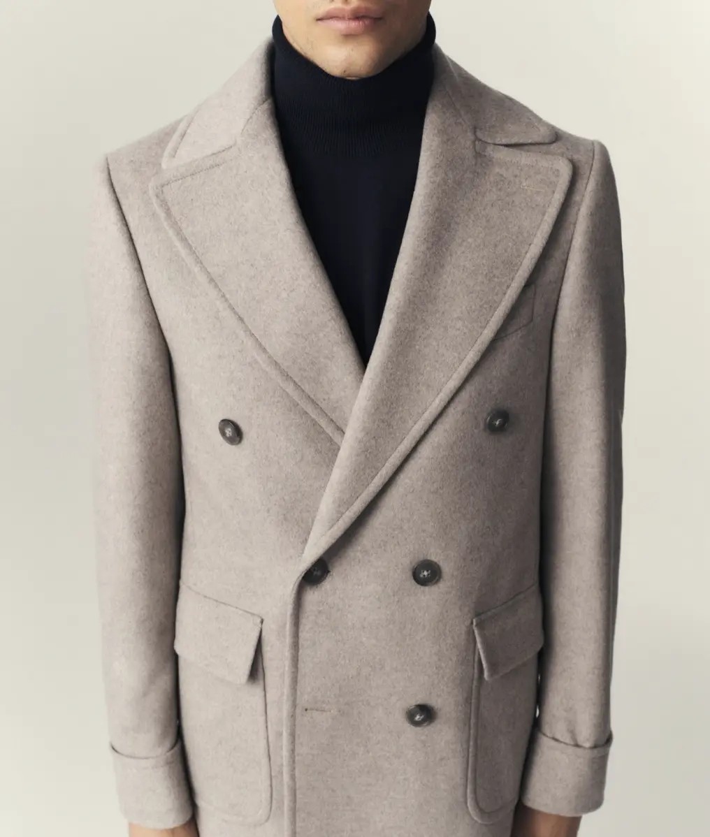 Close up of oatmeal wool overcoat showing peak lapel pick-stitching and dark horn buttons