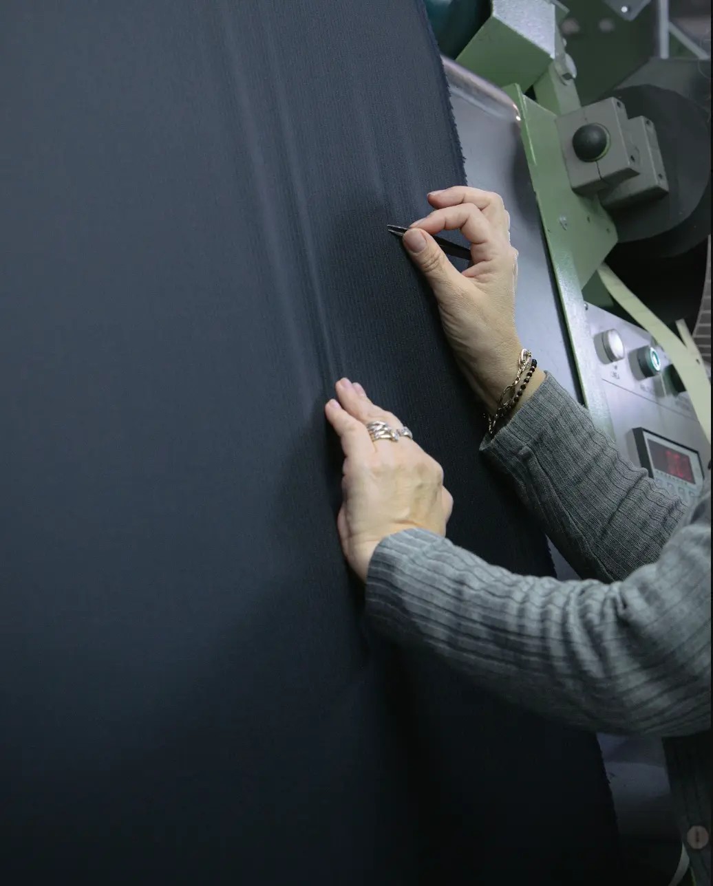 Drago mill worker cutting vibrant blue wool fabric from bolt with Drago Lanificio Biella branding visible