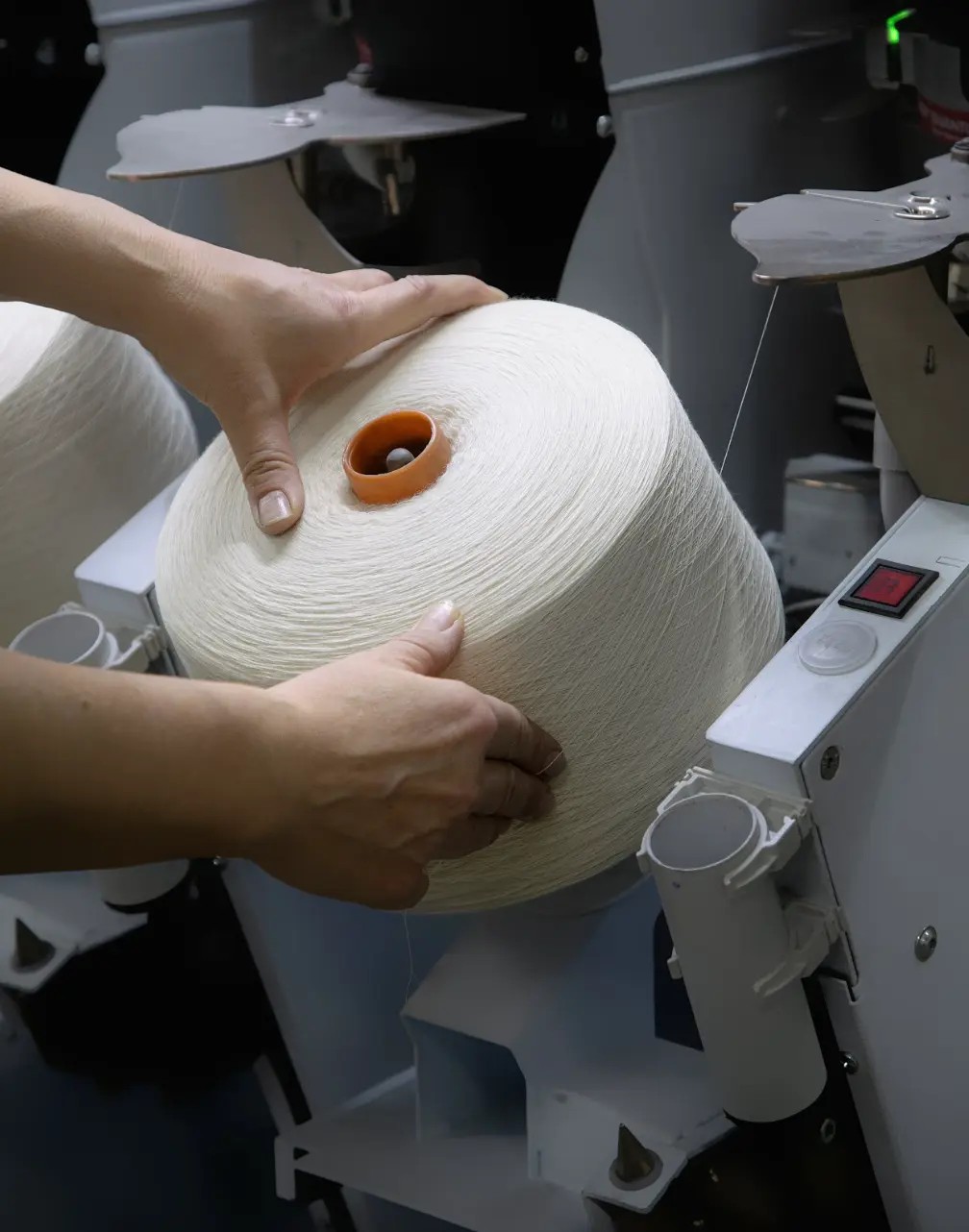Yarn winding process at Drago mill showing ecru wool yarn cones being prepared for weaving in Biella Italy