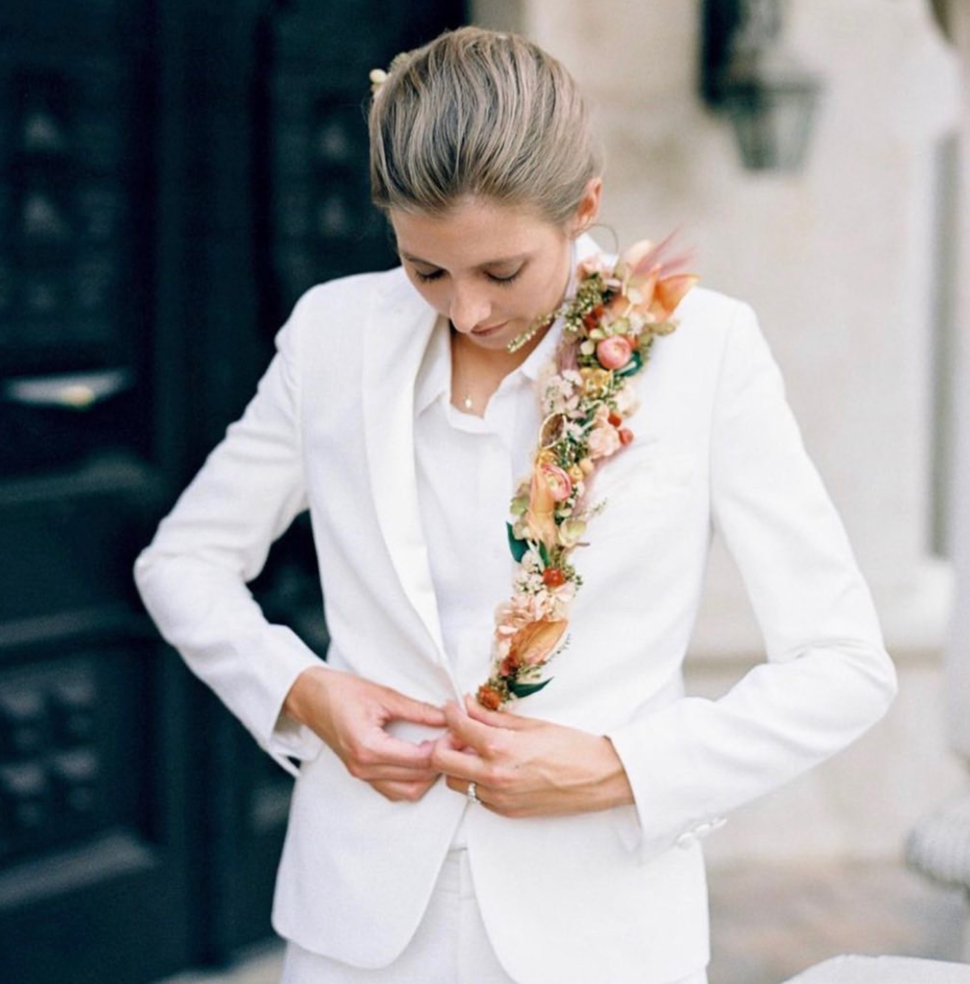 Woman in white suit with floral garland, custom white suit styling by Bespoke By CB