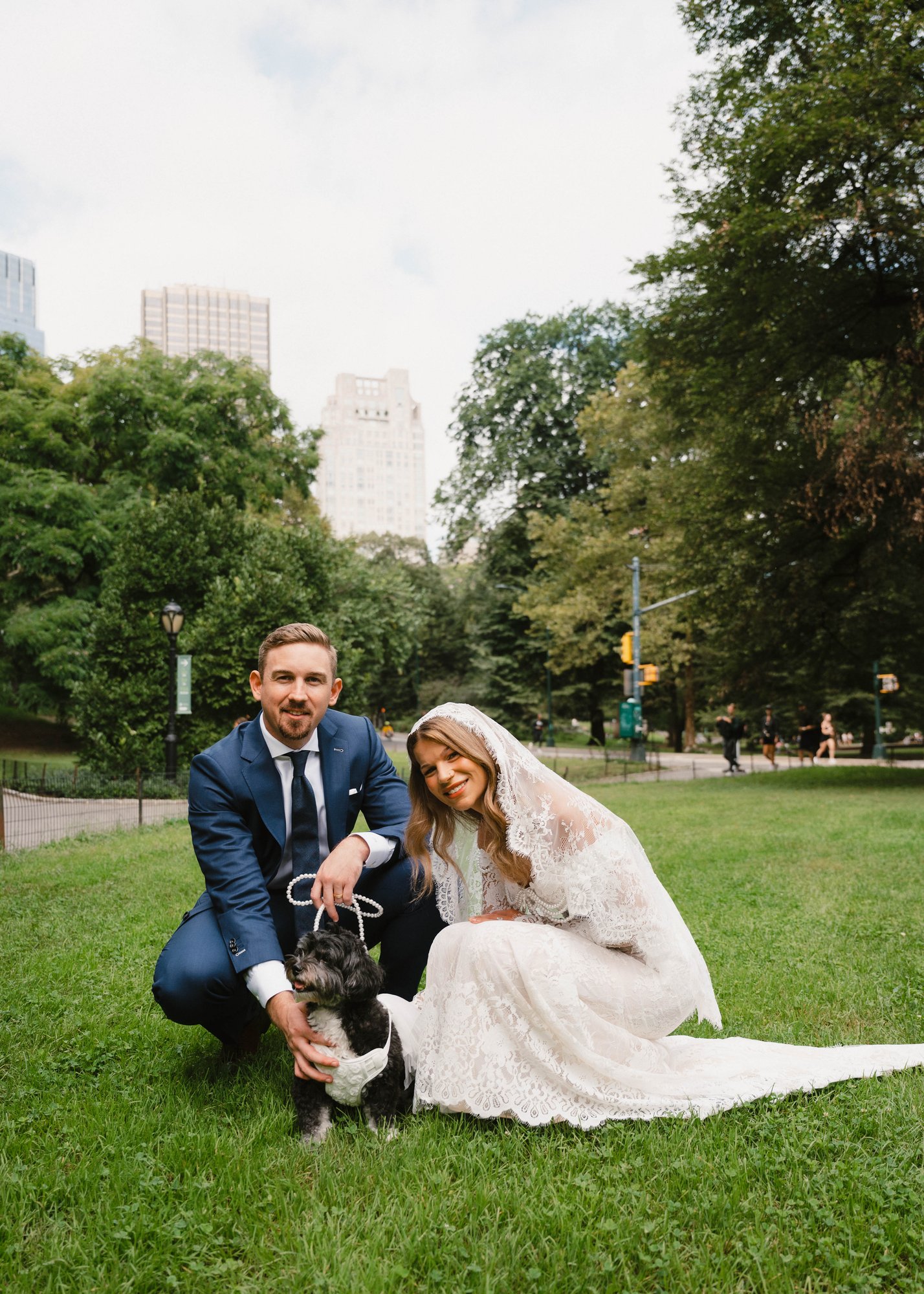 The couple sitting together in a park setting, the custom suit fabric and fit visible in a relaxed wedding moment.