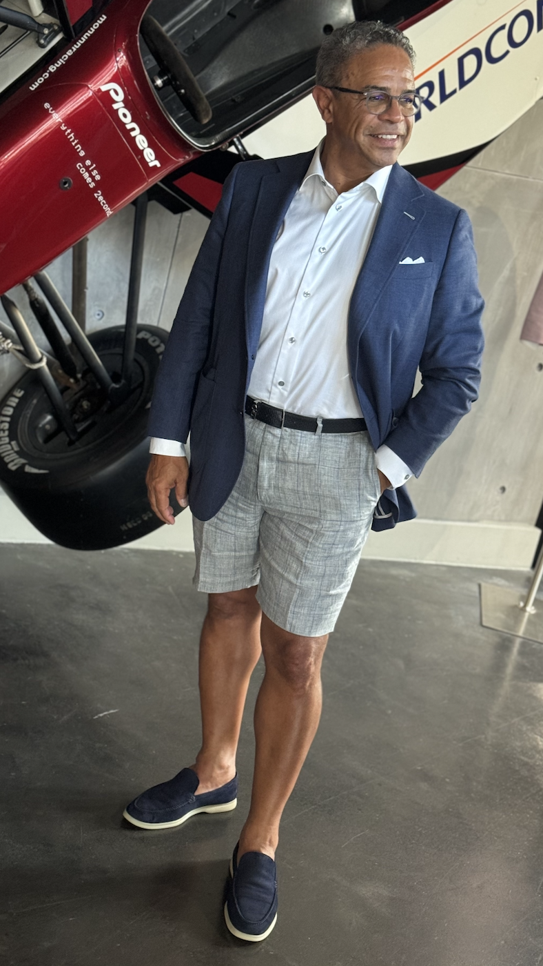 Man wearing a blue blazer with grey windowpane tailored shorts styled with loafers.