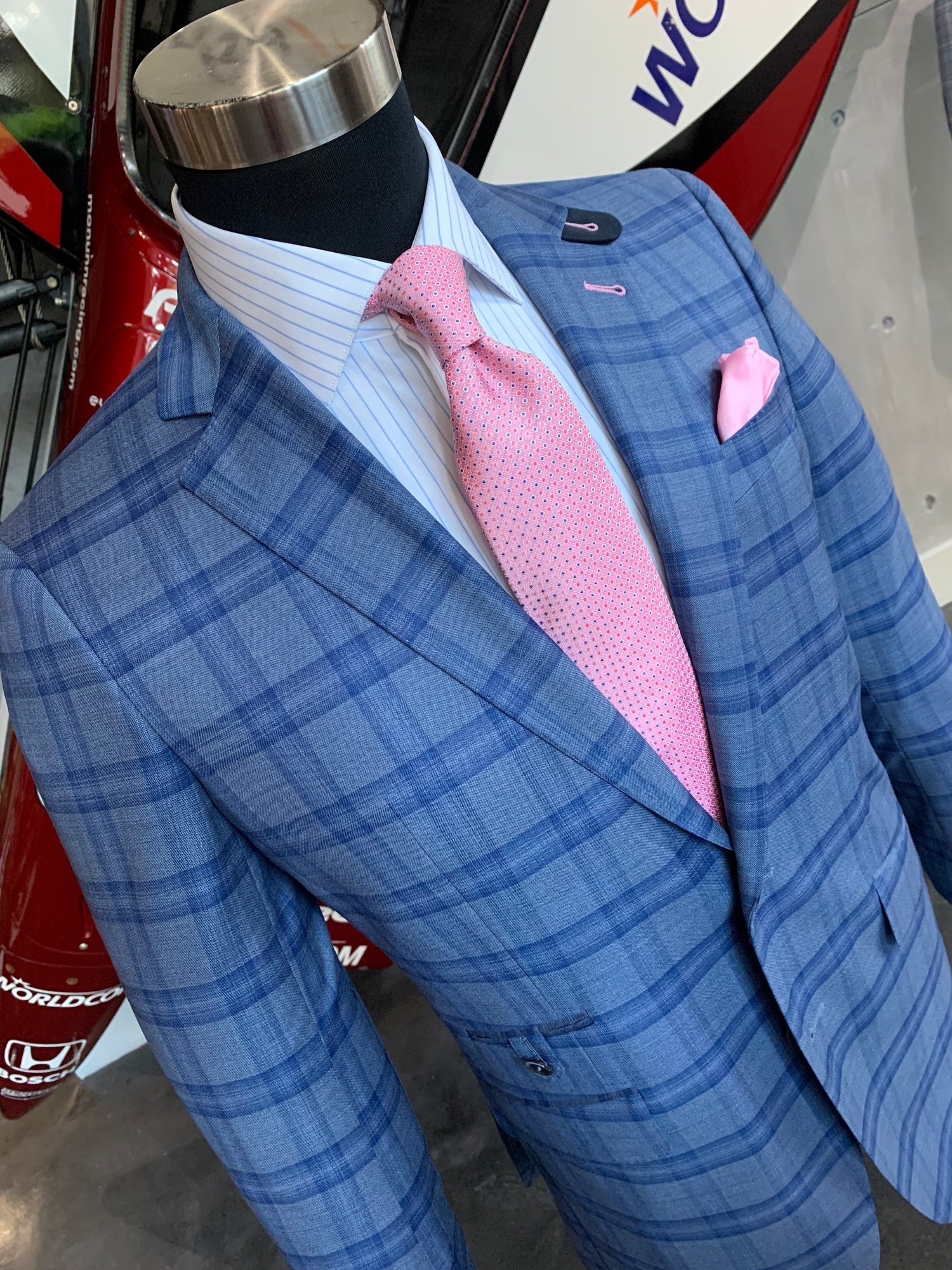 Blue plaid suit jacket with pink dotted tie and pink pocket square on mannequin at Bespoke By CB
