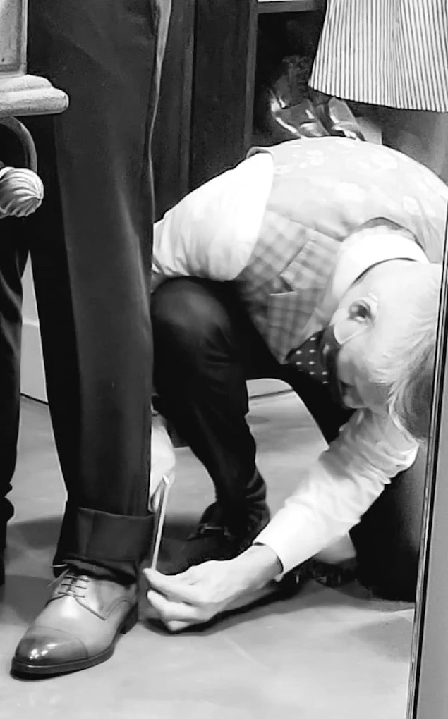 A gentleman adjusting his white pique bow tie while wearing a classic black tailcoat and wing collar shirt.