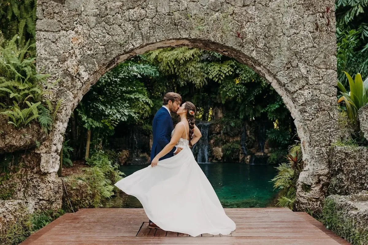 Groom wearing a custom navy blue outdoor wedding suit in a romantic garden setting.