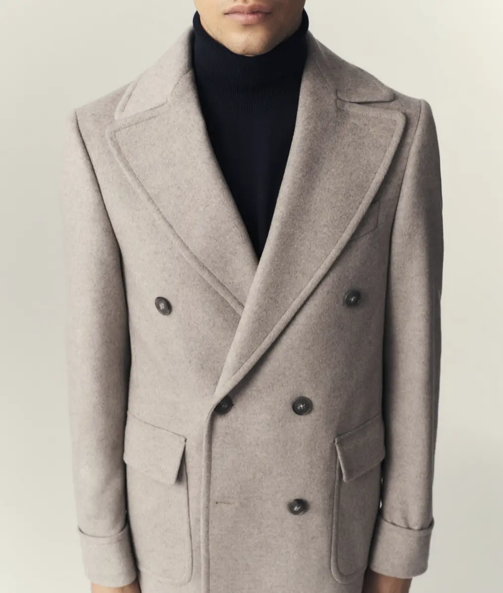Close up of oatmeal wool overcoat showing peak lapel pick-stitching and dark horn buttons