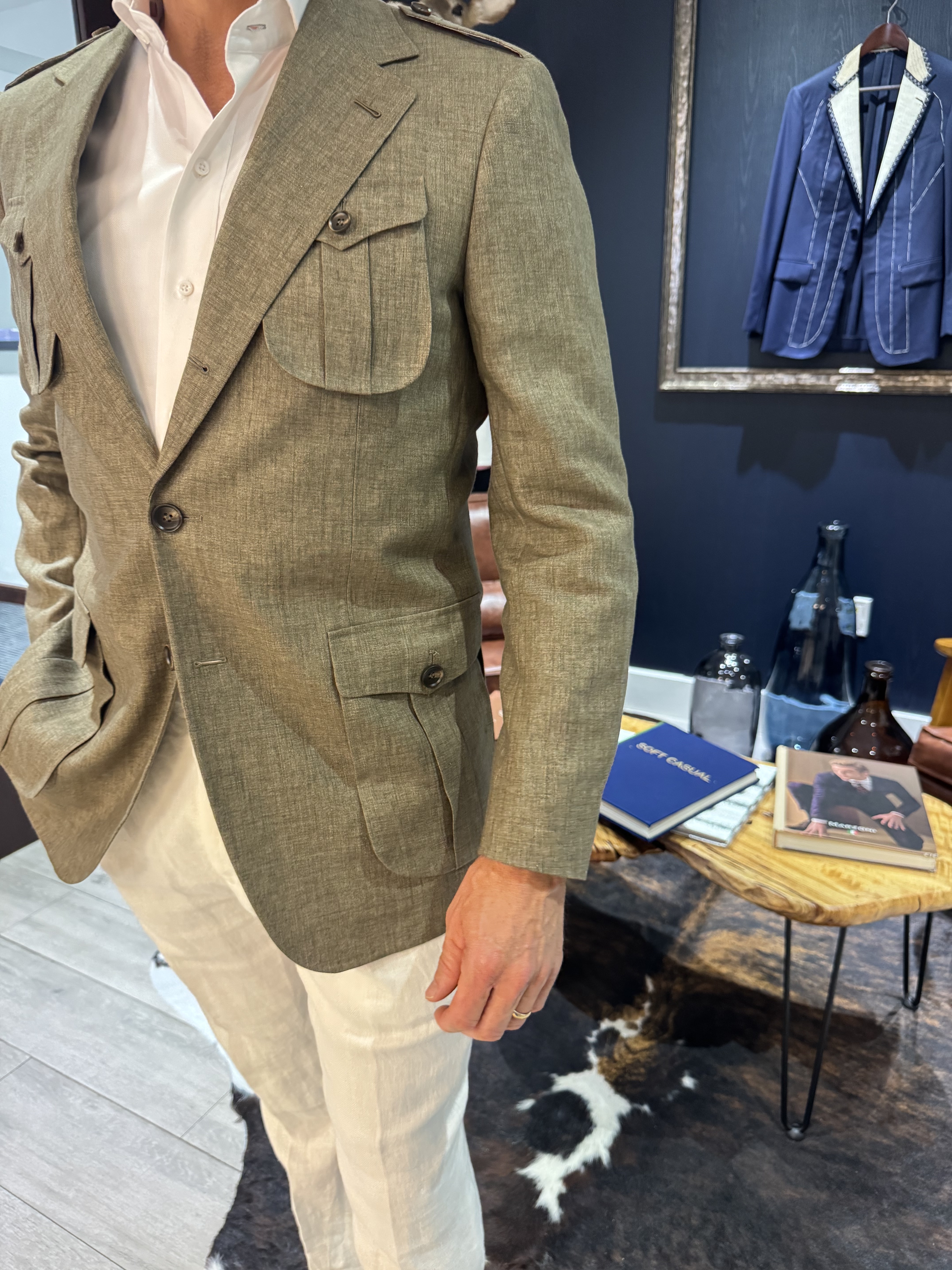 Man wearing olive green safari style custom blazer with white shirt and cream trousers
