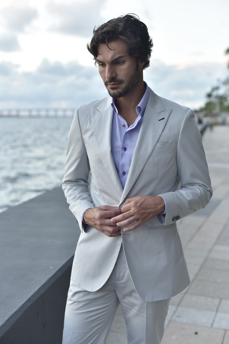 Man in a light-colored summer suit walking along a waterfront promenade, illustrating the bright color palette that suits Miami's tropical environment.