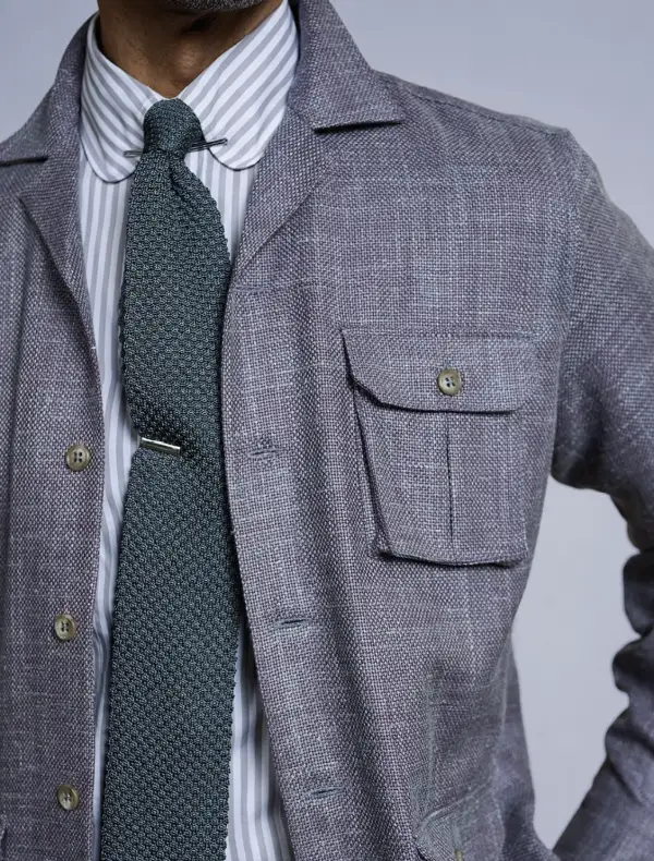 Gray overshirt detail with striped shirt and green knit tie, elevated evening styling