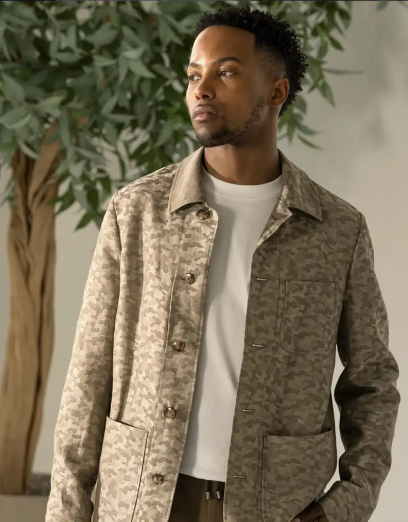 Tan camouflage chore-style shirt jacket over a white t-shirt, relaxed travel layering