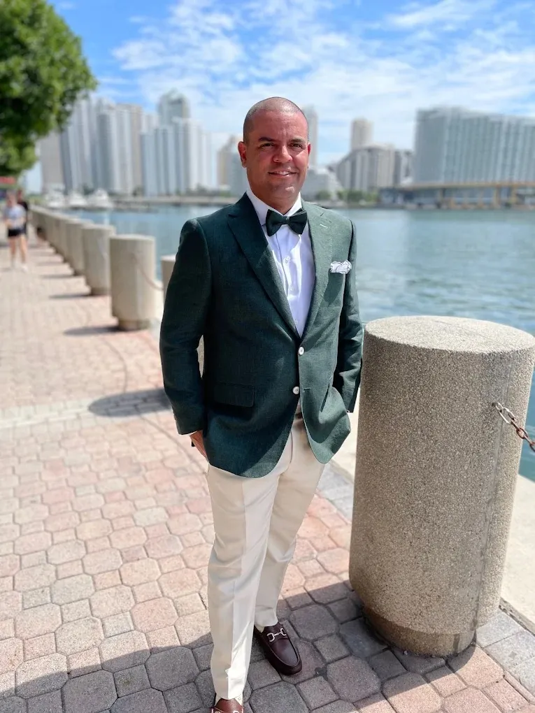 Cream trousers with a green blazer at the waterfront showing summer fabric styling.