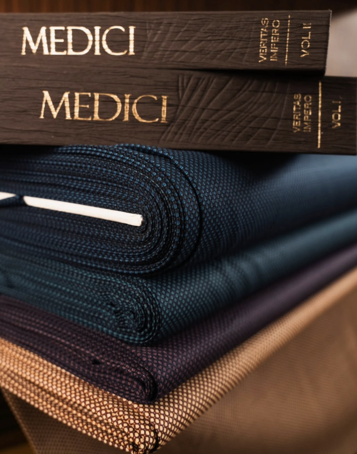 Medici swatch books on folded fabric bolts in navy, charcoal, and tan