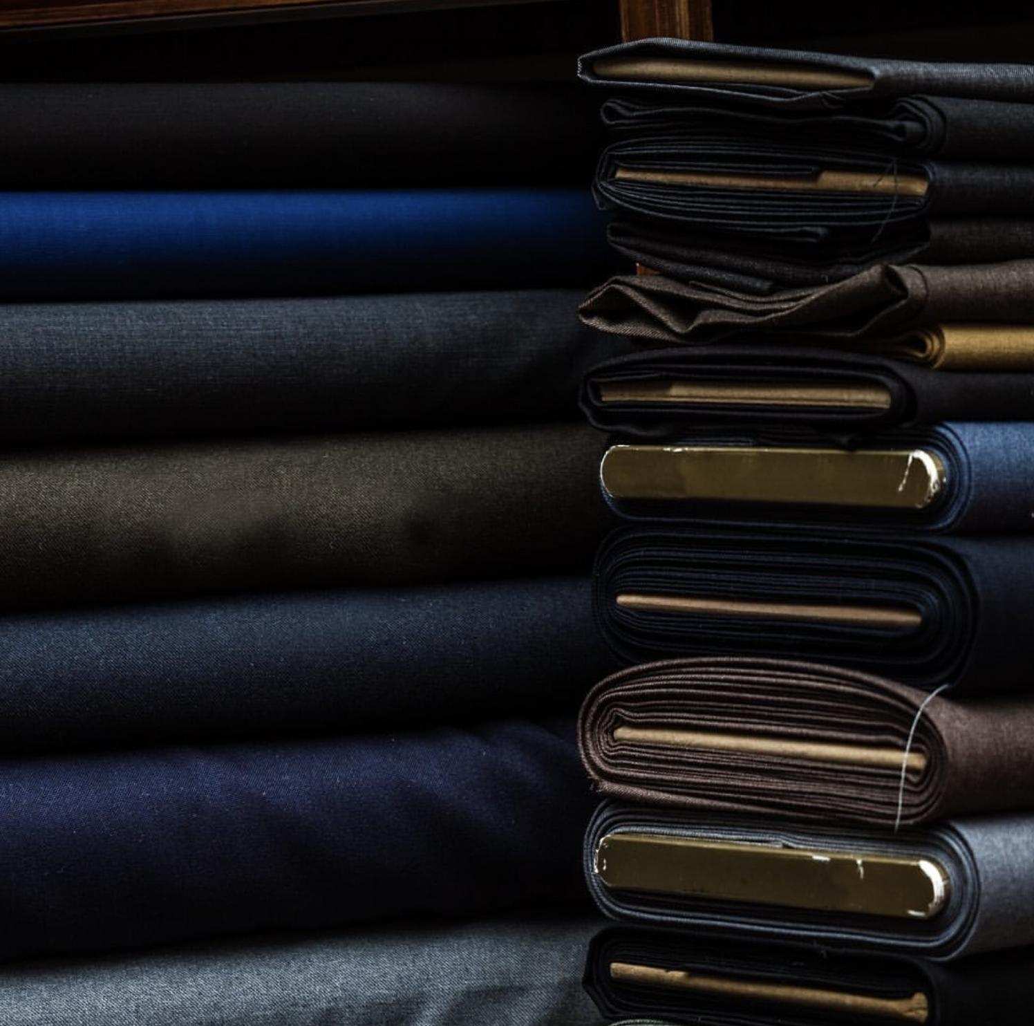 Guabello fabric bolts in navy, charcoal, and brown tones