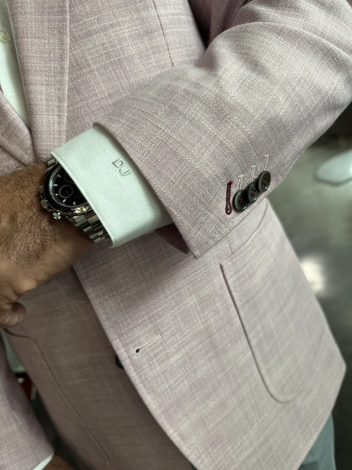 Pink textured blazer with monogrammed shirt cuff and silver watch showing tone-on-tone personalization.