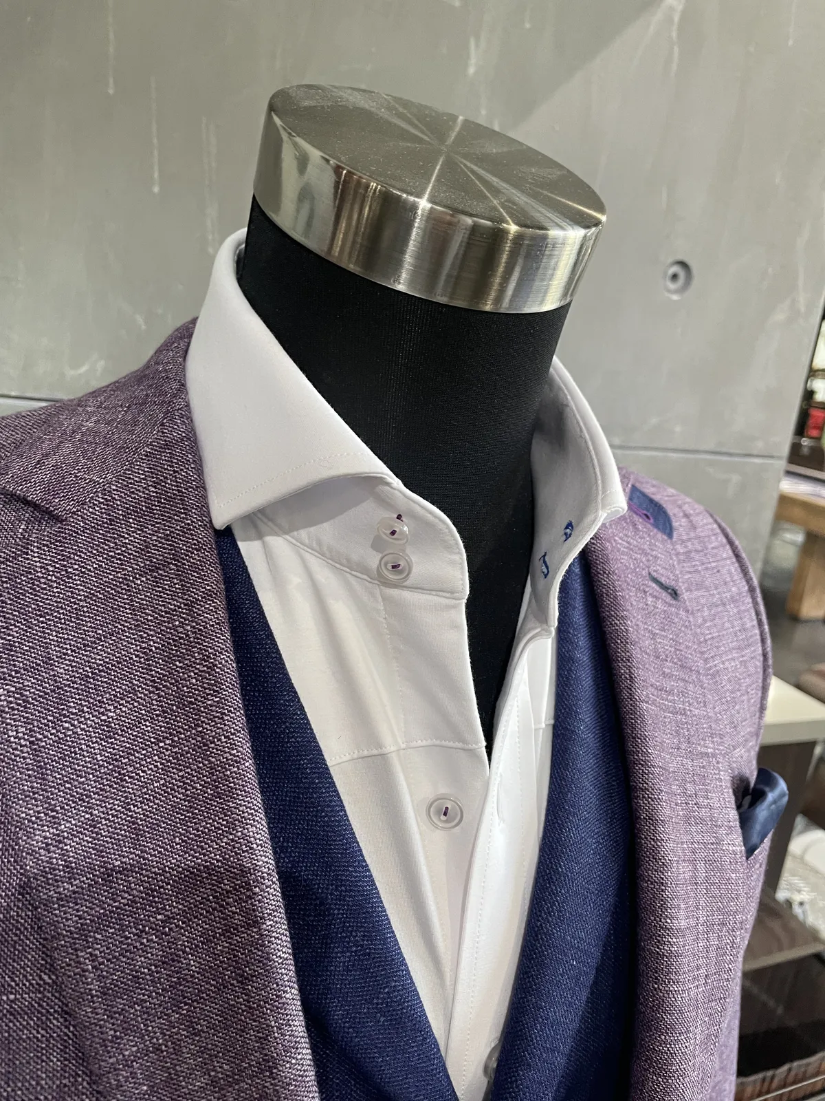 Custom suits: Lilac textured jacket over a navy knit cardigan and white cutaway-collar shirt on a mannequin, with a navy pocket square