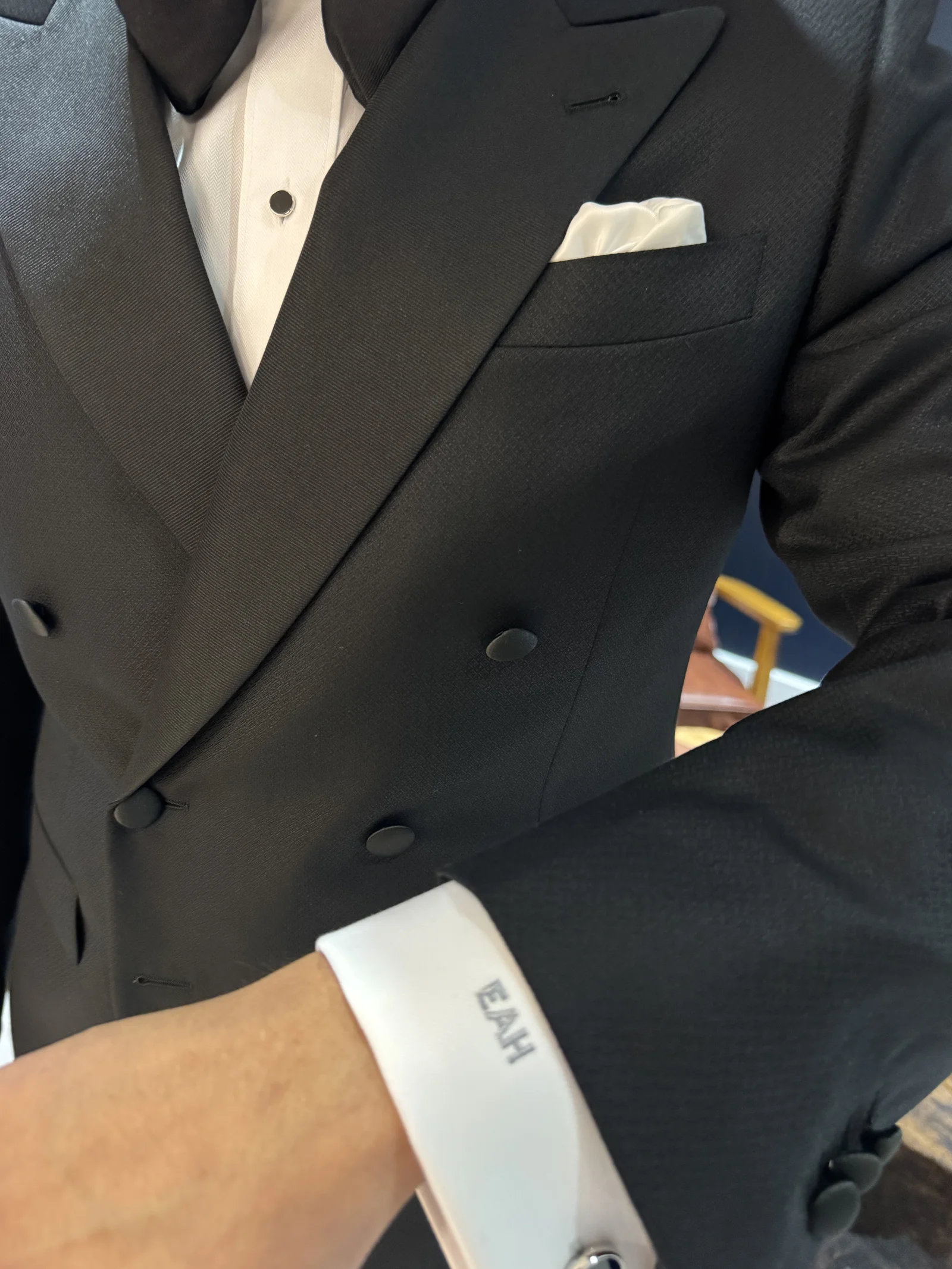 Black tuxedo jacket with white French cuff shirt showing a custom monogrammed cuff.