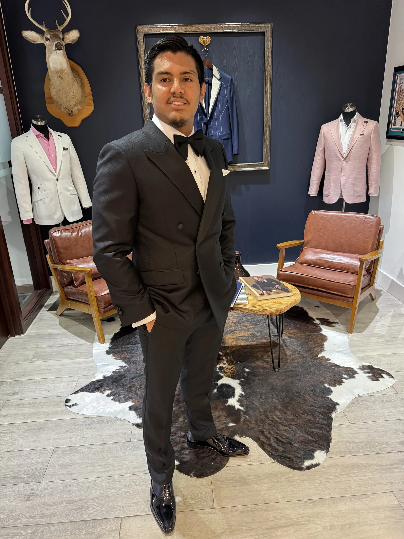 Young man in a black double-breasted tuxedo with peak lapels and bow tie in the showroom.
