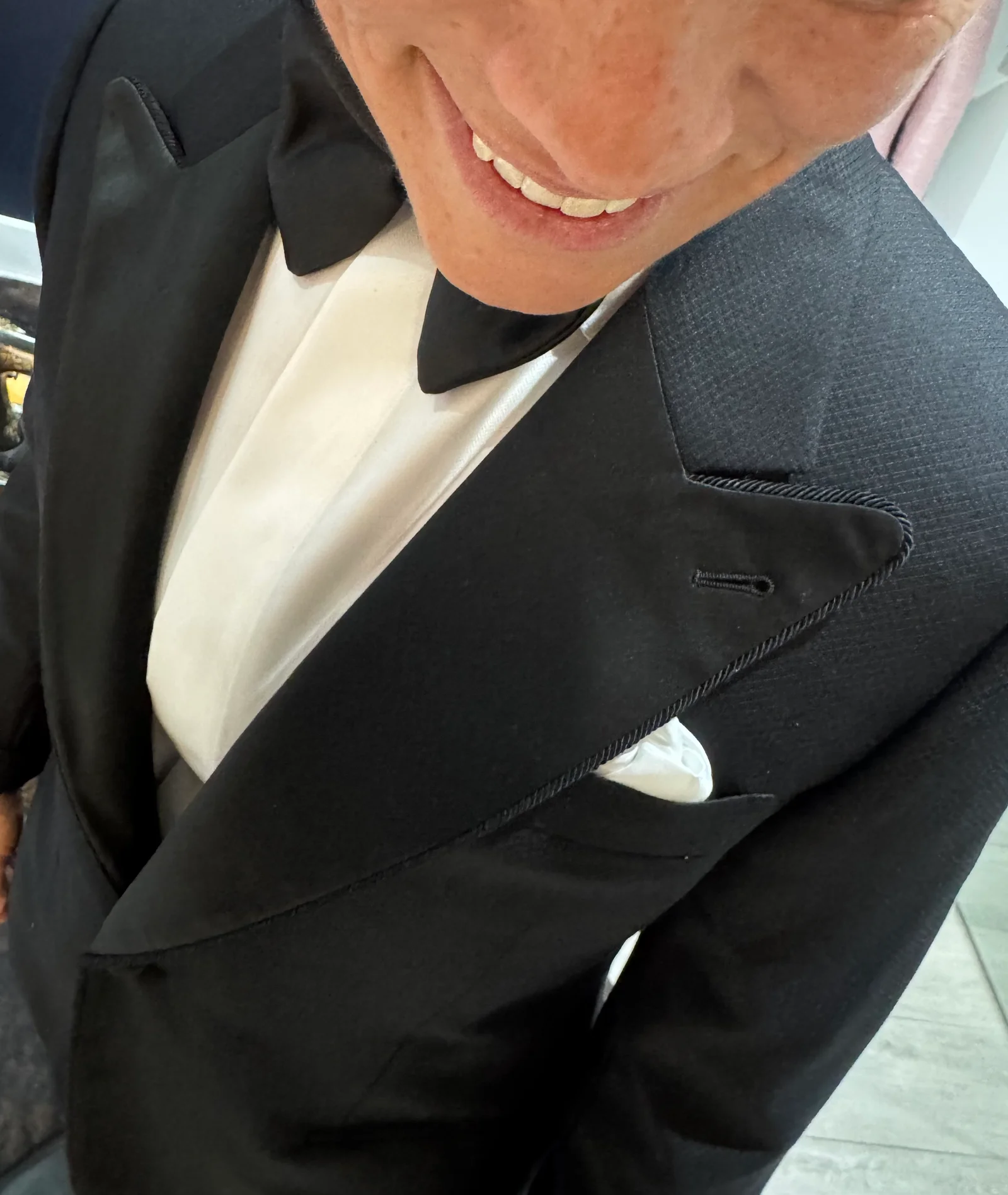 Close up of a textured black tuxedo lapel with silk cording and pocket square.