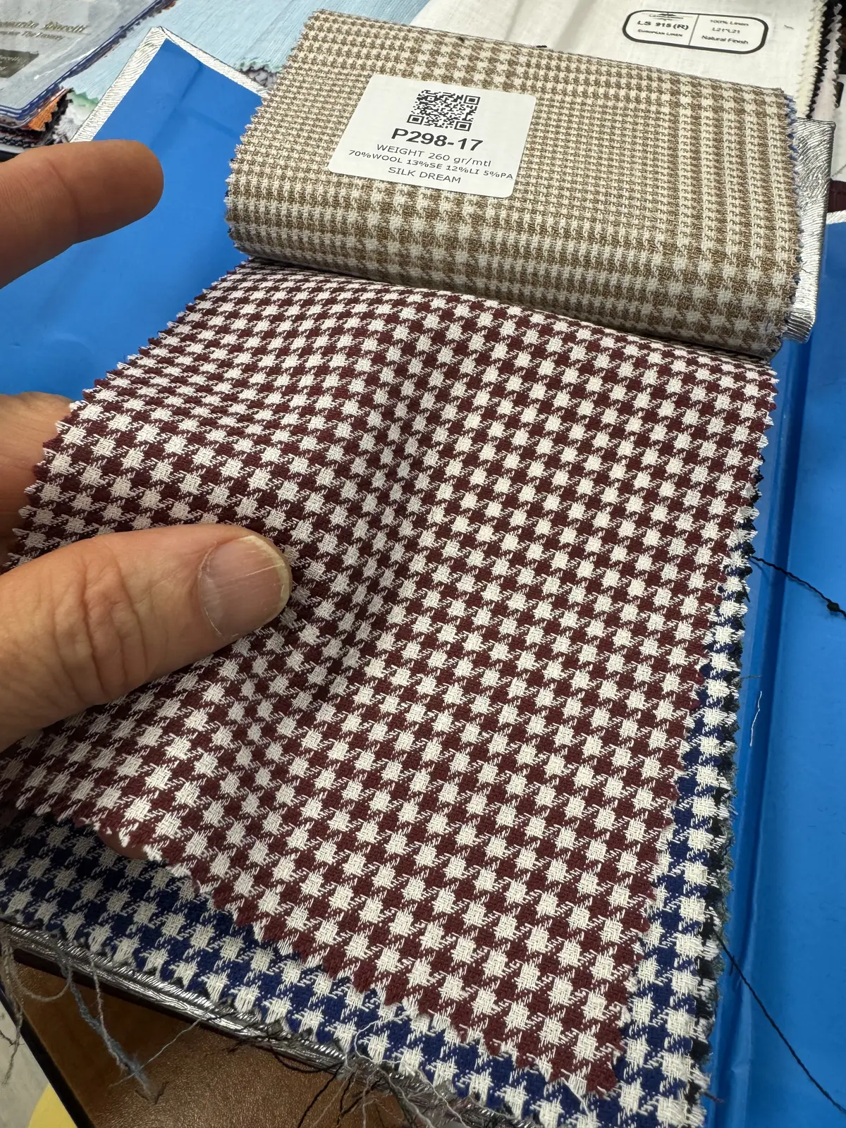 Ariston Silk Dream fabric swatch book showing houndstooth patterns in red, blue, and tan with composition label: 70% wool, 13% silk, 12% linen, 5% polyamide, 260gsm