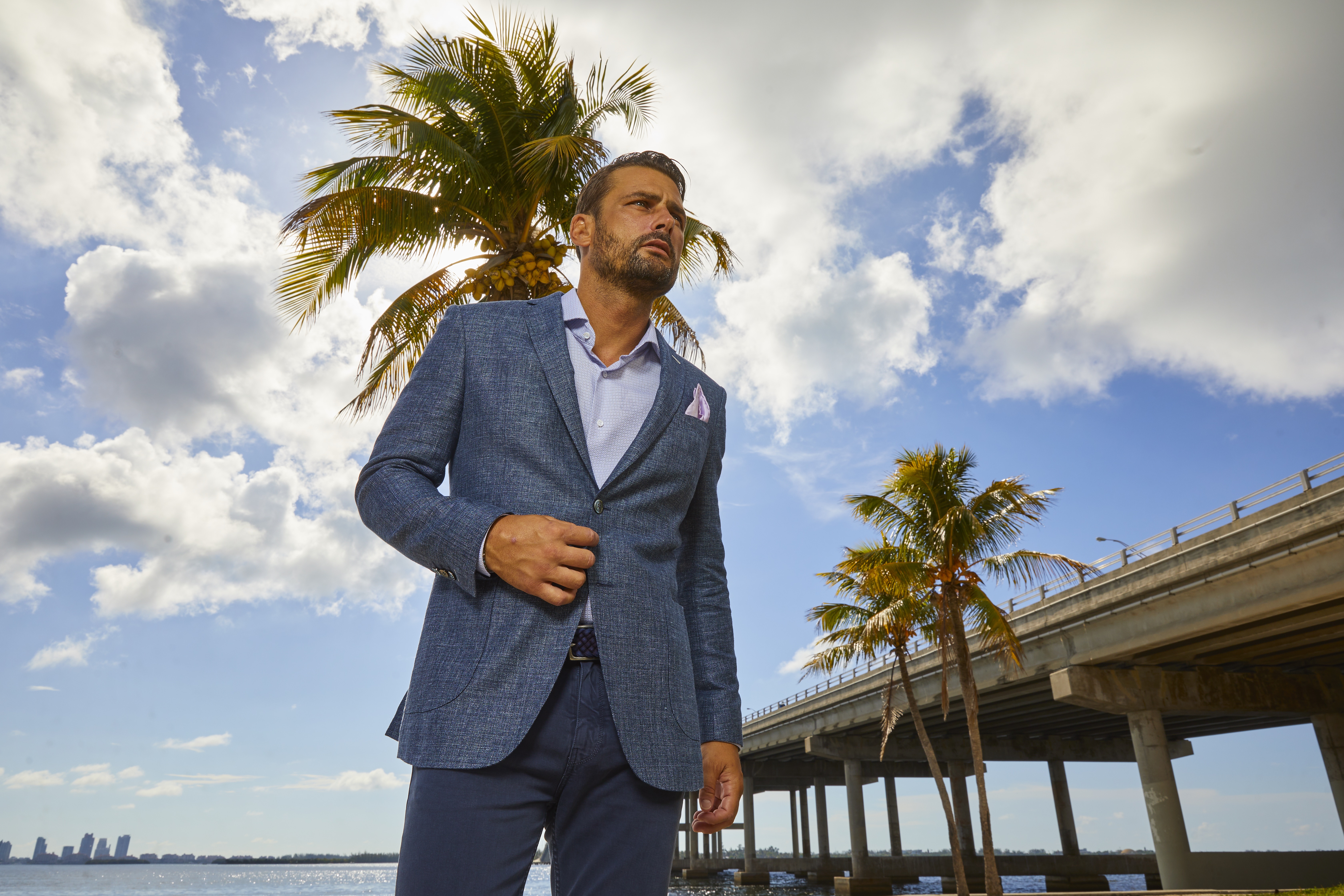 A blue linen textured blazer styled for a warm weather event, representing the kind of versatile piece needed for Miami social occasions.