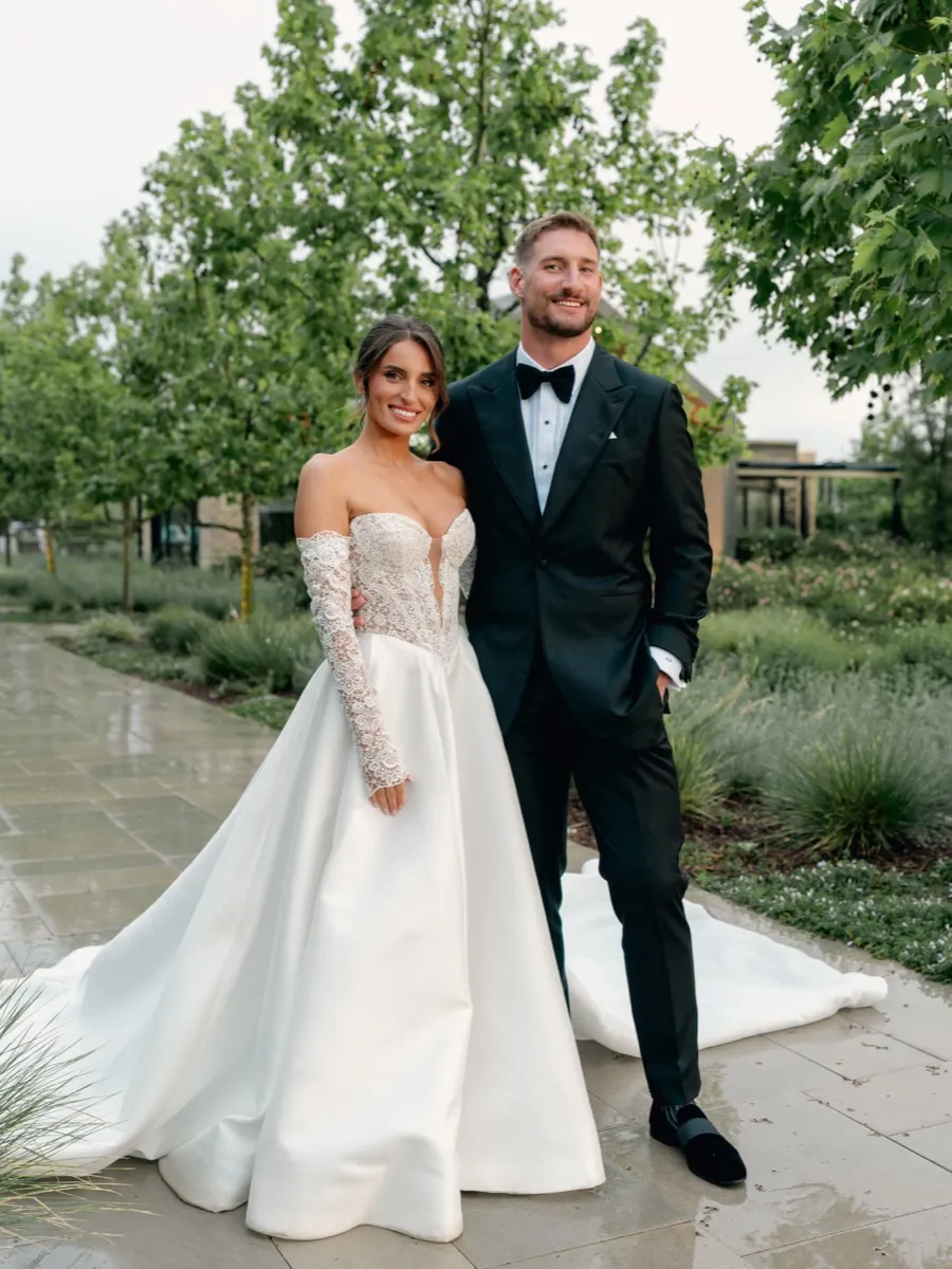 Joey Bosa and Amanda Kassdikian outdoors in their wedding attire, groom in custom black tuxedo by Bespoke By CB