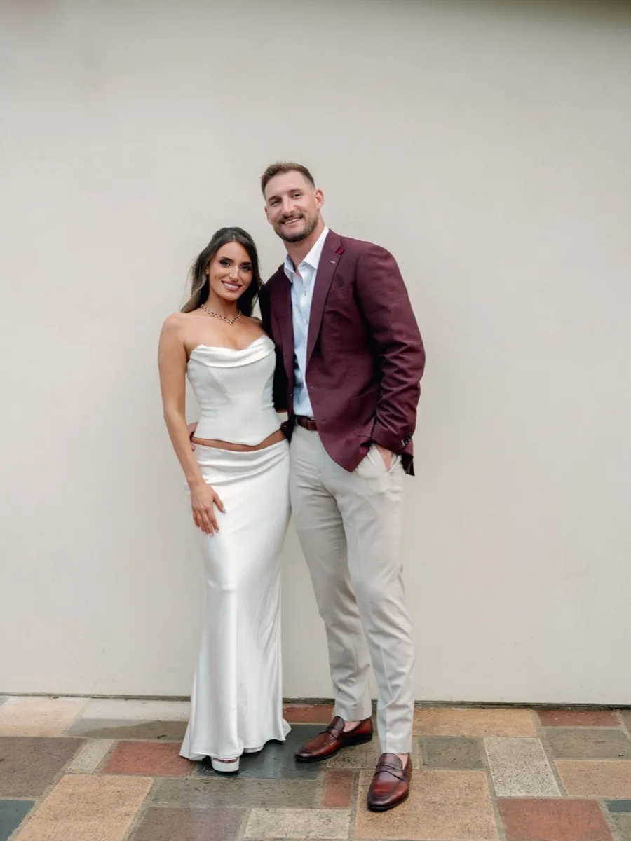 Joey Bosa and Amanda Kassdikian in rehearsal dinner attire, groom in burgundy custom blazer by Bespoke By CB